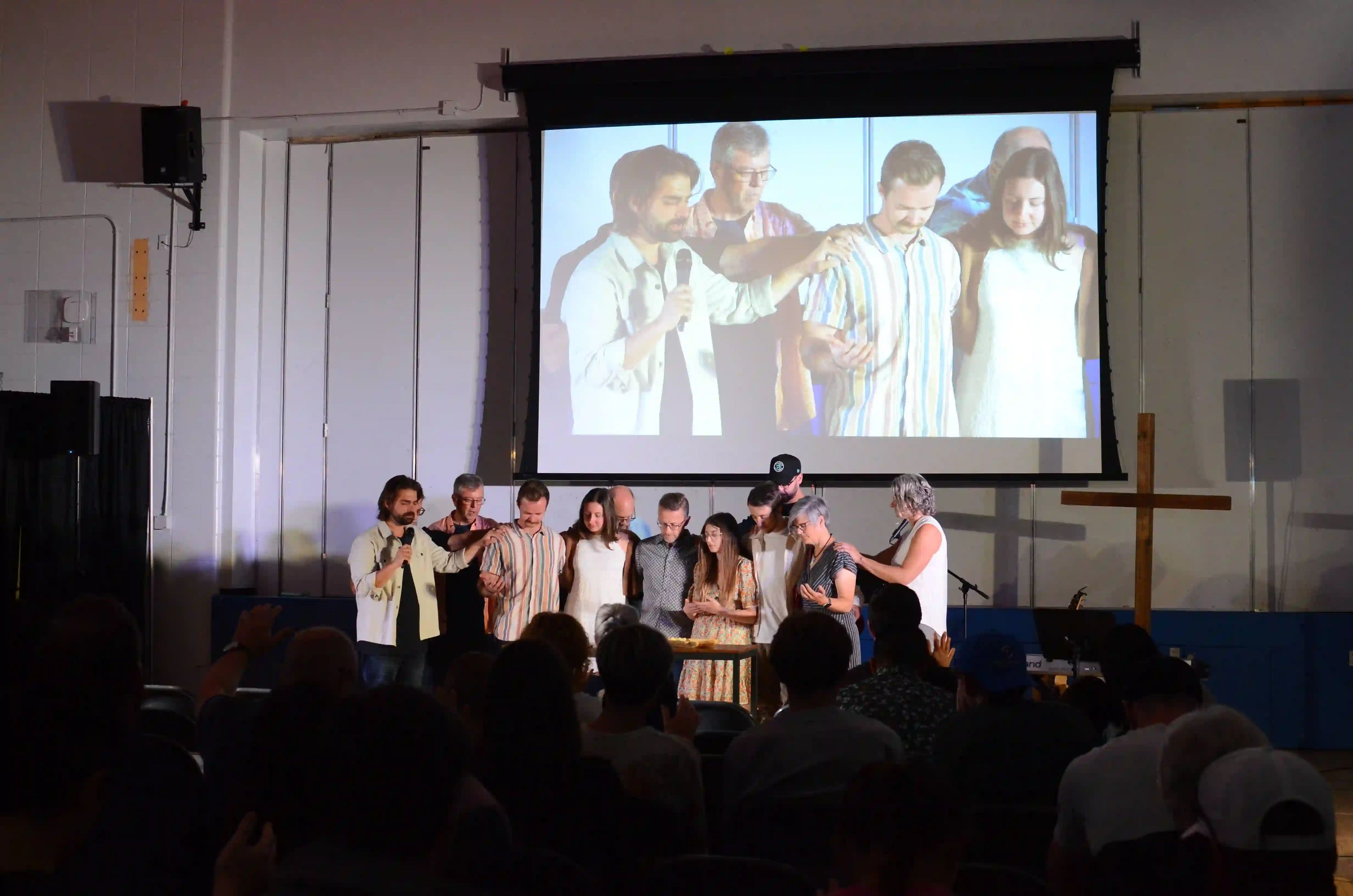 photo of a smiling woman drawing some water with a bottle near a large pipe.